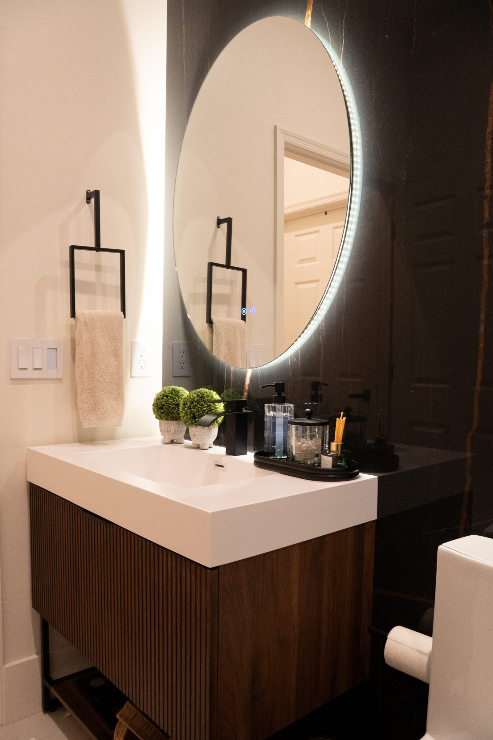 Modern bathroom remodel with fluted wood vanity, backlit LED round mirror and walk-in shower — R&S General Construction Orlando